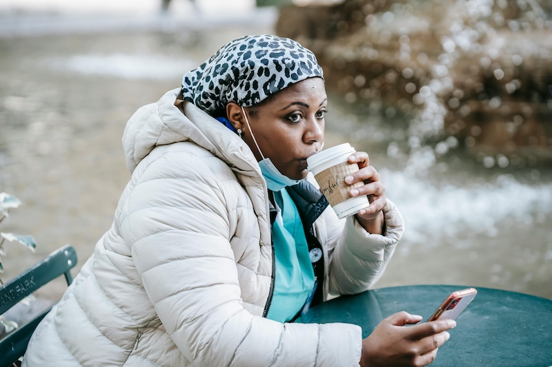 A medical resident drinking coffee and scrolling their phone on their break