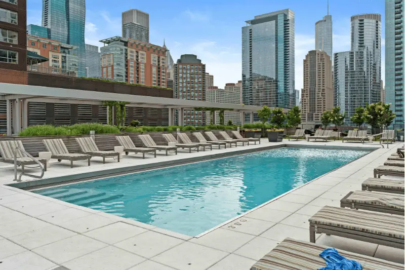 The pool at 500 Lake Shore Drive apartments is surrounded by lounge chairs, towering high-rises and sunny blue skies. 